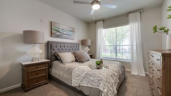 A bedroom with a bed, nightstand, and window.